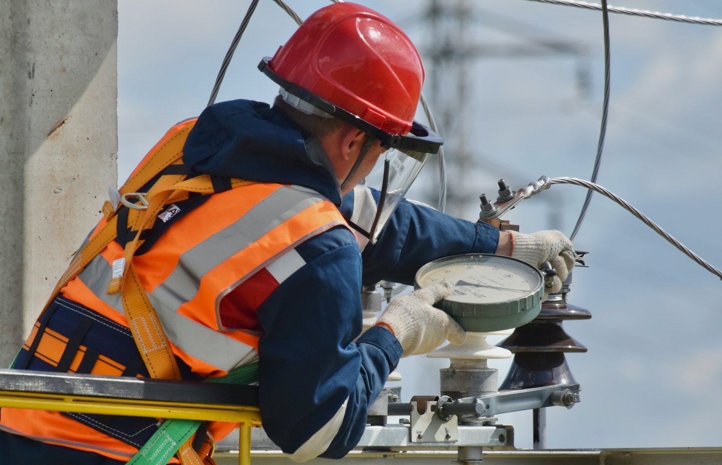 Technicien en tenue de sécurité ajustant du matériel électrique en extérieur.