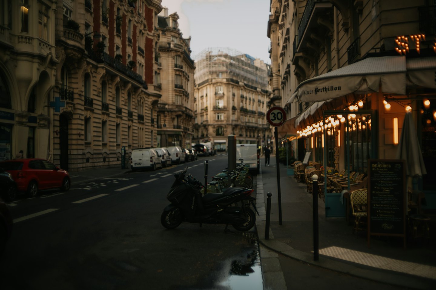 Café parisien avec chaises en rotin sous un auvent rayé.
