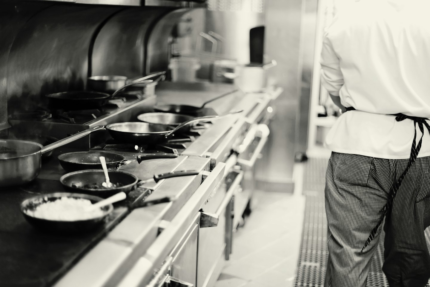 Un chef en uniforme cuisine dans une cuisinière en acier inoxydable.