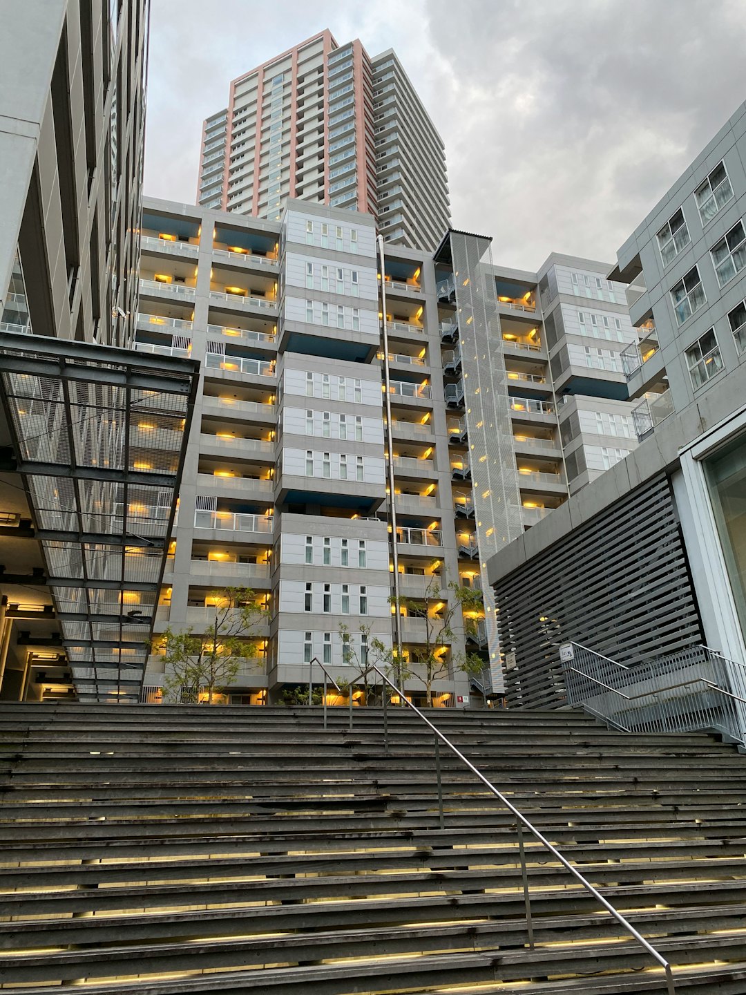 Immeuble d'appartements urbain moderne avec fenêtres éclairées et escaliers en béton.