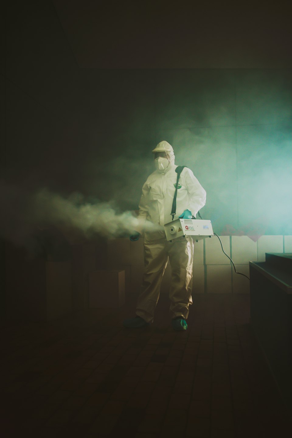 Un agent d'assainissement en combinaison hazmat utilise une machine de pulvérisation.